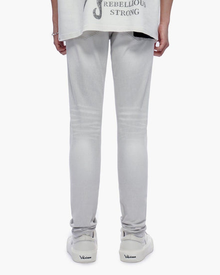 Person wearing light gray pants and a white shirt with text on a white background