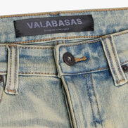 Close-up of a denim garment with 'VALABASAS' label on a white background