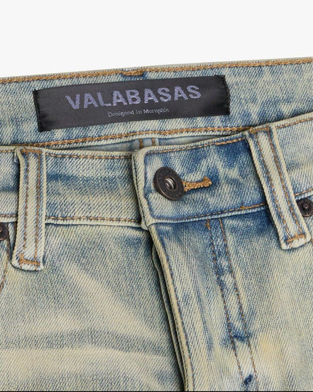 Close-up of a denim garment with 'VALABASAS' label on a white background