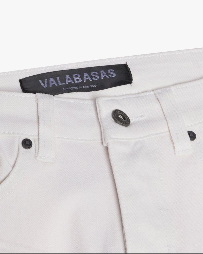 Close-up of white pants with a visible brand label on a white background