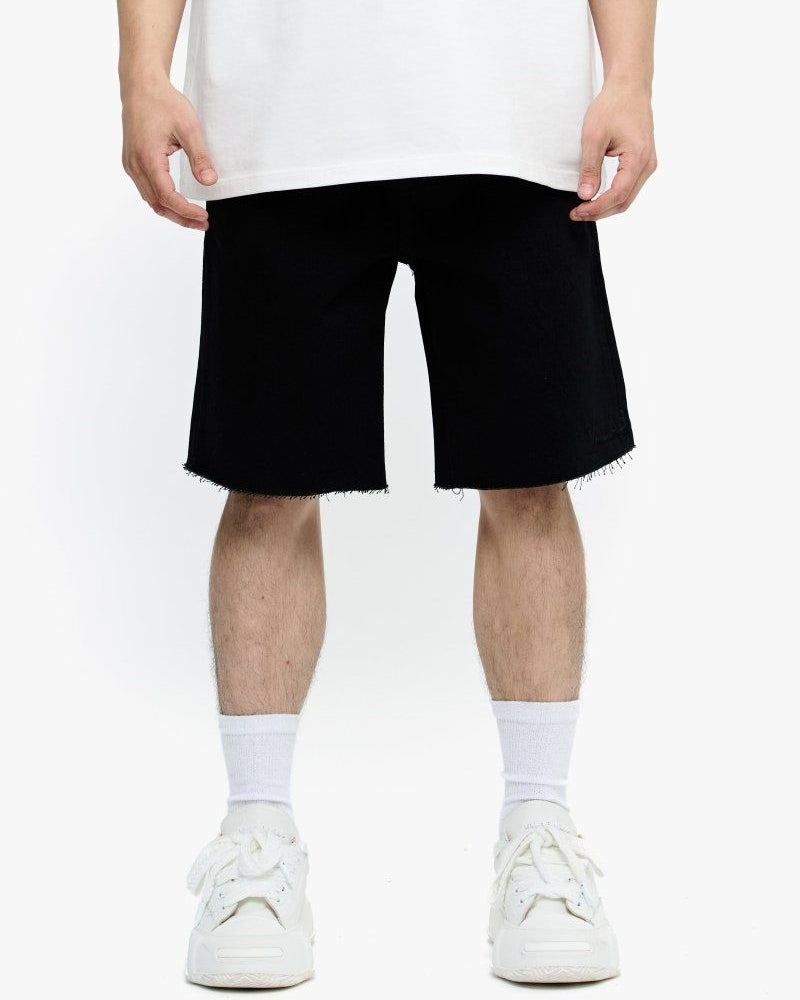 Person wearing black shorts and white sneakers on a white background