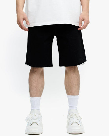 Person wearing black shorts and white sneakers on a white background