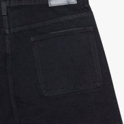 Close-up of black pants with a visible brand label on a white background