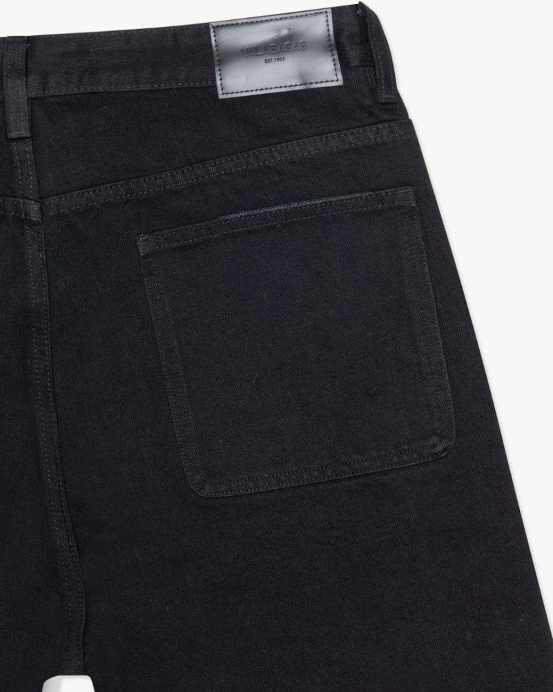 Close-up of black pants with a visible brand label on a white background