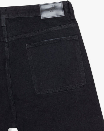 Close-up of black pants with a visible brand label on a white background