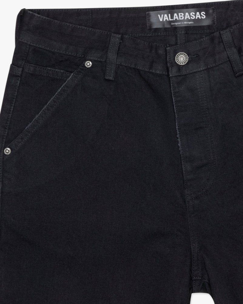 Close-up of black pants with a visible brand label on a white background