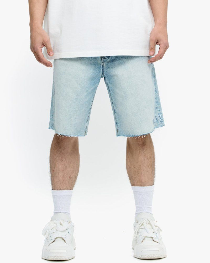 Person wearing light blue denim shorts and white sneakers on a white background