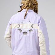 A person shown from the back wearing a light lavender windbreaker jacket with cream-colored sleeves and a moon-phase cutout design across the upper back. The jacket features a large 'JP' monogram logo in the center.