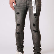 Person wearing gray distressed jeans with white sneakers on a white background