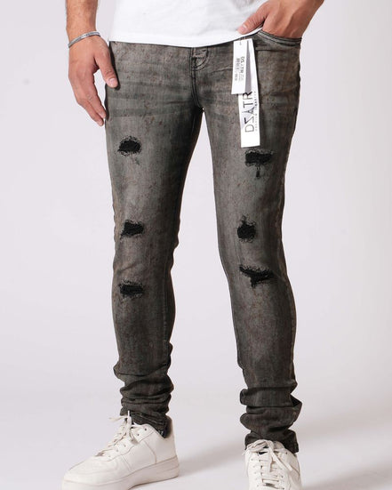Person wearing gray distressed jeans with white sneakers on a white background