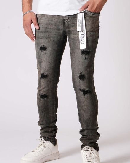 Person wearing gray distressed jeans with white sneakers on a white background