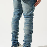 Person wearing blue jeans and white sneakers on a light gray background