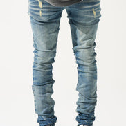 Person wearing distressed blue jeans and white sneakers on a light gray background