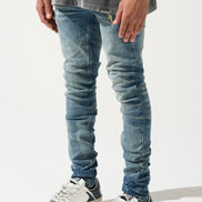 Person wearing blue jeans and white sneakers on a white background