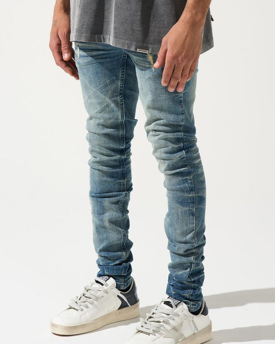 Person wearing blue jeans and white sneakers on a white background