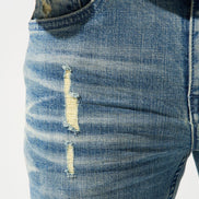 Close-up of distressed blue jeans with a white background