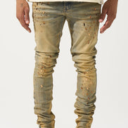 Person wearing distressed beige jeans and white sneakers on a white background