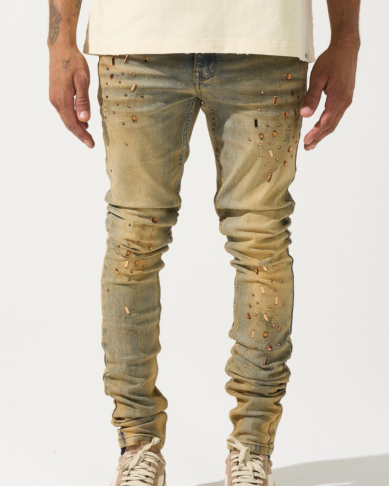 Person wearing distressed beige jeans and white sneakers on a white background