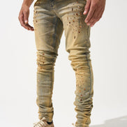 Person wearing distressed beige jeans and matching sneakers on a white background