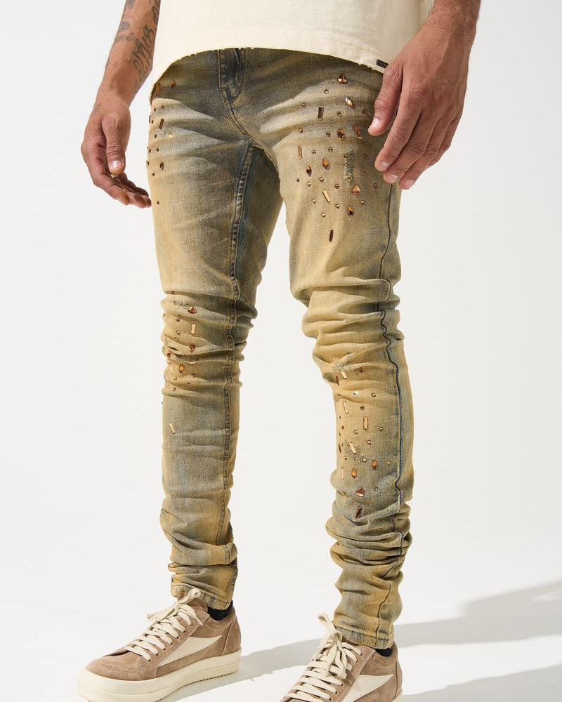 Person wearing distressed beige jeans and matching sneakers on a white background