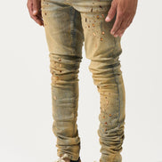 Person wearing distressed beige jeans and matching sneakers on a white background