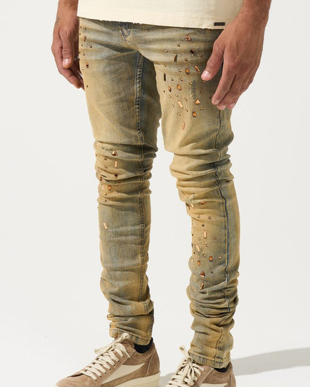 Person wearing distressed beige jeans and matching sneakers on a white background
