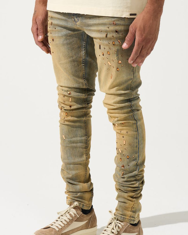 Person wearing distressed beige jeans and matching sneakers on a white background
