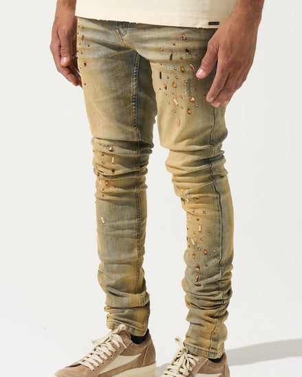 Person wearing distressed beige jeans and matching sneakers on a white background
