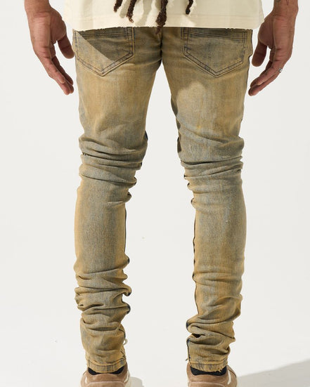 Person wearing light brown distressed jeans on a white background