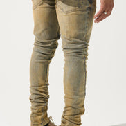 Person wearing distressed beige jeans and brown sneakers on a white background