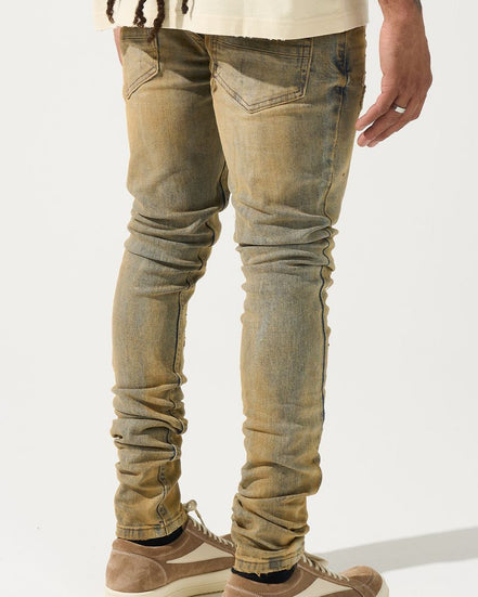 Person wearing distressed beige jeans and brown sneakers on a white background