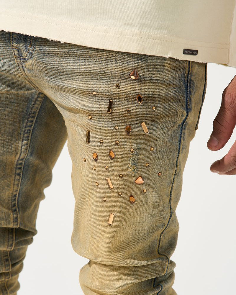 Close-up of beige pants with decorative studs on a white background