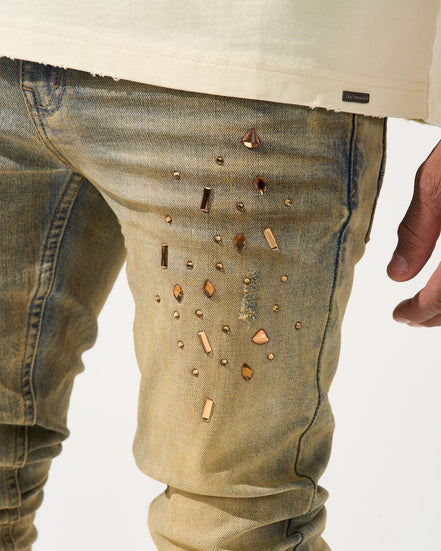 Close-up of beige pants with decorative studs on a white background