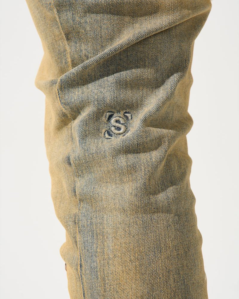 Close-up of beige pants with a logo on a white background