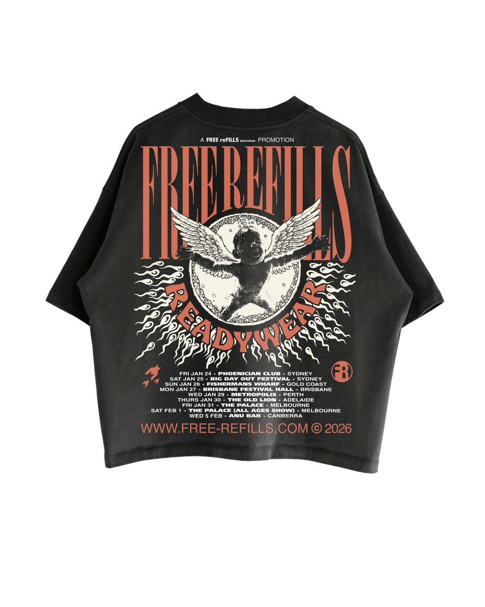 A black short-sleeve graphic T-shirt laid flat against a white background, featuring a large front print with the words 'FREE REFILLS' and 'READY WEAR' in orange-red lettering, a winged cherub motif, and small white text including 'A FREE REFILLS PUBLICATION' and a website at the bottom.