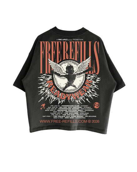A black short-sleeve graphic T-shirt laid flat against a white background, featuring a large front print with the words 'FREE REFILLS' and 'READY WEAR' in orange-red lettering, a winged cherub motif, and small white text including 'A FREE REFILLS PUBLICATION' and a website at the bottom.