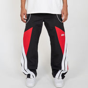 Black track pants with red and white accents worn by a person on a white background
