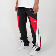 Person wearing black and red track pants with a logo on a white background