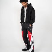 Person wearing a black hoodie and black pants with red and white accents on a white background