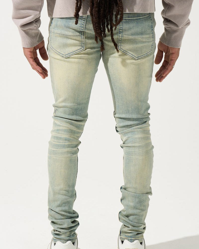 Person wearing light blue jeans and white sneakers on a white background