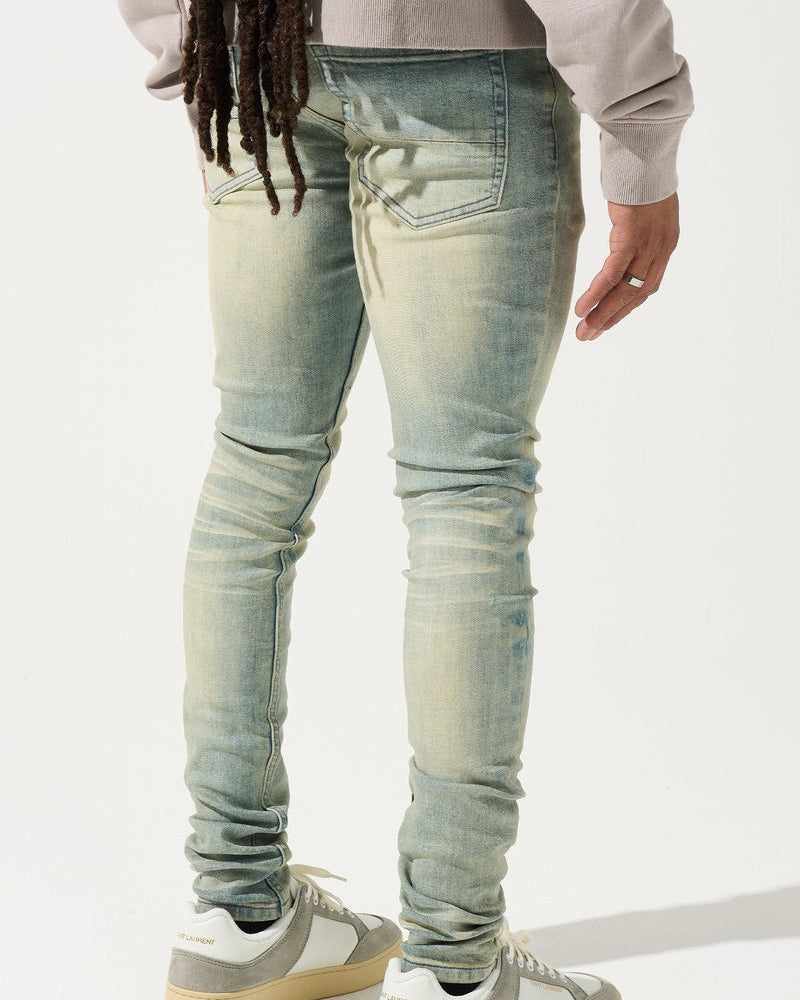 Person wearing light blue jeans and white sneakers on a white background