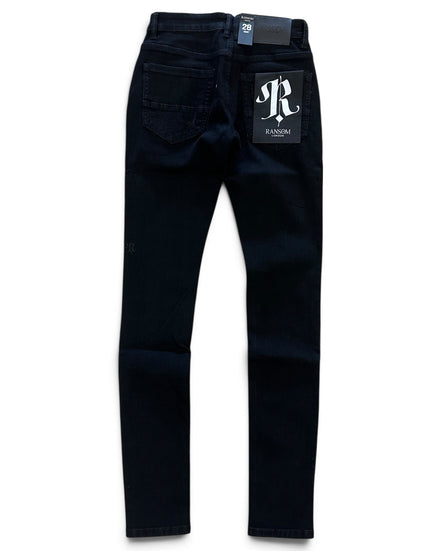 Dark navy blue slim-fit jeans shown from the back, featuring a white 'JR RANSOM' logo patch on the back pocket and a brand tag at the waistband, set against a plain white background.