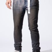 A person wearing slim-fit dark gray washed denim jeans with distressed details and white sneakers, shown from the waist down against a plain white studio background.