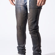 A person wearing slim-fit dark gray washed jeans with distressed details and white sneakers, shown from the waist down against a plain white studio background.