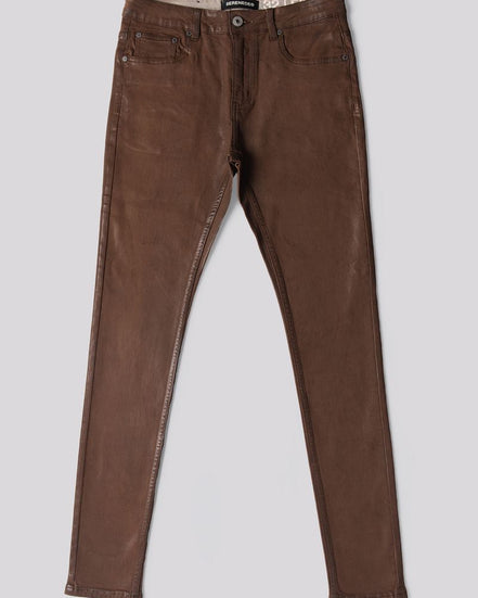 A pair of slim-fit brown jeans laid flat against a solid light gray background.