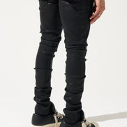 Person wearing black distressed jeans and black sneakers on a white background