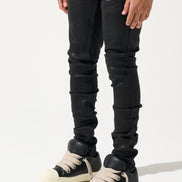 Person wearing black distressed jeans and black sneakers on a white background