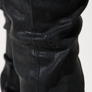 Close-up of black pants with a visible brand logo on a white background