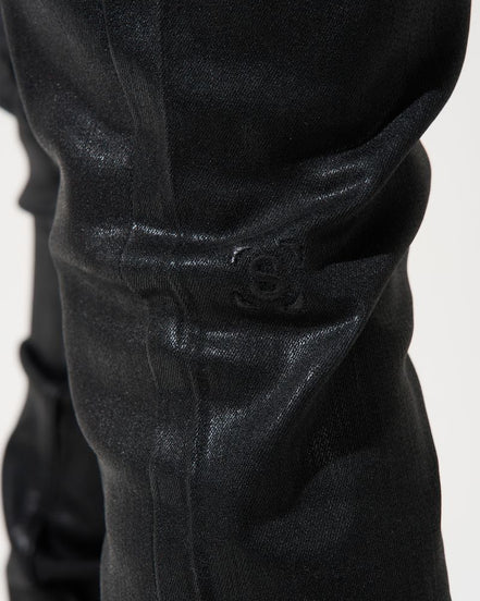 Close-up of black pants with a visible brand logo on a white background