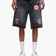 Person wearing black denim shorts with patches on a white background